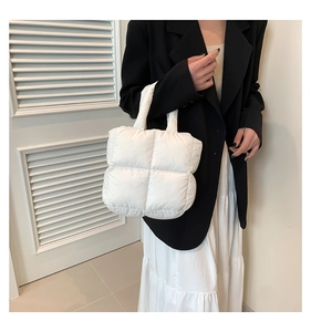 Detail of white quilted puffer tote bag with soft padded handles and grid texture