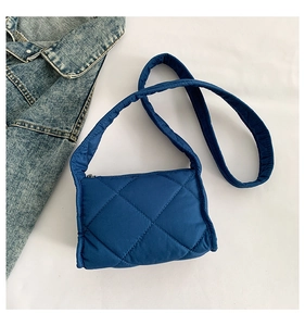 Detail van blauwe gewatteerde tas met ruitpatroon en soepele ritssluiting aan de bovenkant