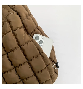 Close-up of brown quilted bag showing a practical side pocket holding a smartphone