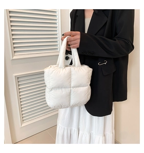 Detailed view of a white quilted down tote bag with soft padded handle and square texture