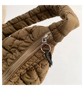 Macro detail of brown quilted bubble bag showing padded nylon fabric and metal zipper