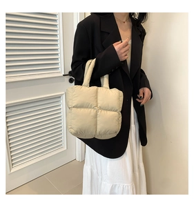 Detail of quilted puffer tote bag in cream white with soft padded handles and casual style