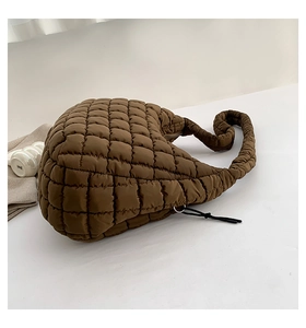 Macro detail of brown quilted puff shoulder bag with silver zipper and textured fabric