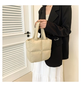 Close-up of beige quilted down puffer tote bag featuring soft square stitching detail