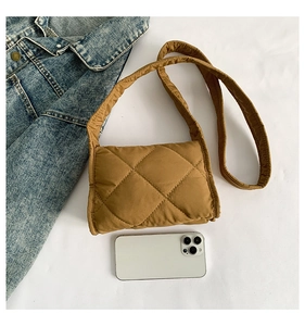 Detail van karamel gewatteerde nylon schoudertas met zachte textuur en een telefoon
