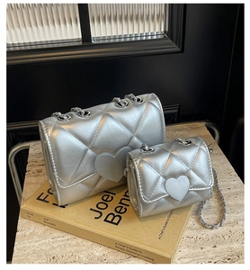 Close-up of silver quilted chain bag with heart buckle and metallic leather texture