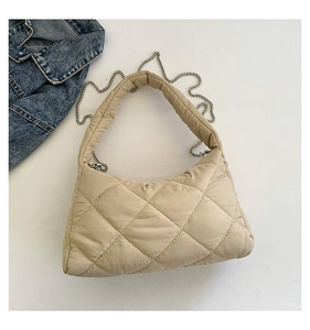 Détail d'un sac à bandoulière matelassé beige avec surpiqûres losanges et chaîne argent