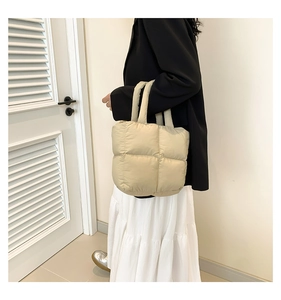 Detailed view of beige puffer tote bag with quilted square patterns and padded handle