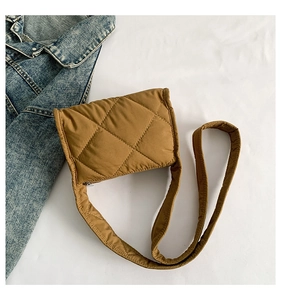 Detail van bruine gewatteerde crossbodytas met ruitpatroon en denim jack accent