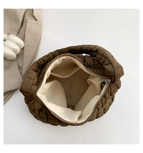 Macro view of dark brown quilted puffer bag showing beige lining and inner pocket