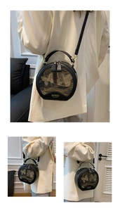 Detail of black round handbag featuring golden butterfly embroidery and metal zipper