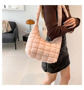 Detailed view of pink quilted puffer hobo bag worn by a person in a minimalist interior