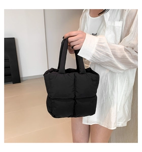 Close-up of black quilted puffy tote bag showing soft square texture and handle details