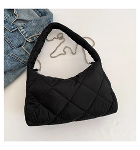 Détail d'un sac matelassé noir avec chaîne métallique et accessoire en jean