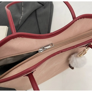 Detail of nude pink faux leather tote with burgundy trim and silver zipper closure