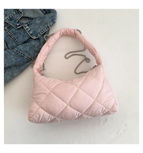 Détail du sac bandoulière matelassé rose avec chaîne argentée sur veste en jean