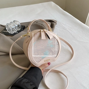 Detail of round pale pink crossbody bag with exquisite building embroidery and top handle