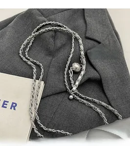 Close-up of a silver chain strap with an adjustable gold ball buckle on a quilted bag