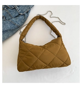 Détail du sac matelassé marron montrant la texture bouffante et la bandoulière chaîne