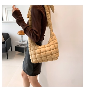 Detalle de bolso bandolera acolchado beige con textura moderna de plumón en una modelo