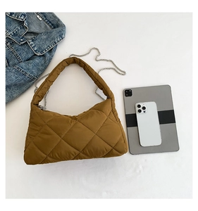 Détail du sac bandoulière matelassé avec chaîne argentée et large sangle sur fond blanc