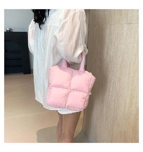 Detailed side view of pink quilted puffer tote bag held by model in neutral studio setting