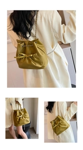 Detalle del bolso tipo cubo amarillo con lazo decorativo y correa de cadena de metal
