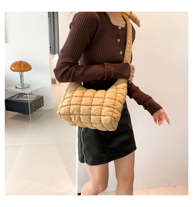 Detalle de bolso bandolera acolchado caqui con costuras cuadradas y correa ancha de hombro