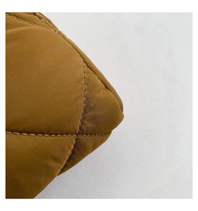 Vue macro du tissu en nylon matelassé caramel avec coutures en losange sur le sac bandoulière