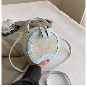 Detailed view of light blue round bag with gold-tone hardware and landscape embroidery