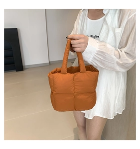 Close-up of orange quilted puffer tote bag featuring soft square padded texture
