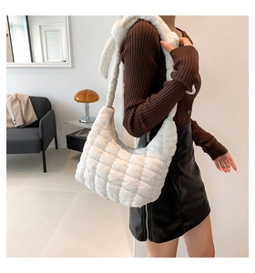 Detalle de bolso acolchado blanco con asa de nudo mostrado en ambiente hogareño