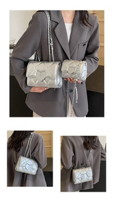 Detail view of silver quilted crossbody bag with heart patch and chain strap