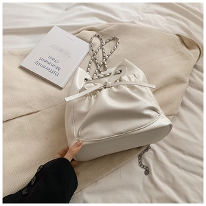 Detalle de bolso saco de cuero blanco con cordón de lazo y correa de cadena plateada