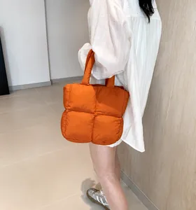 Close-up of bright orange quilted down tote bag with a soft padded texture for daily use