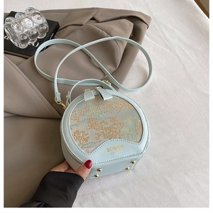 Detail of round mint green handbag with floral embroidery and golden brand logo