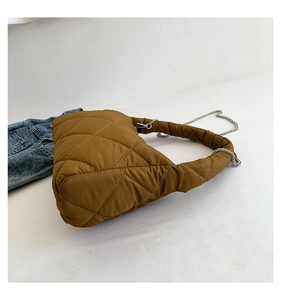 Détail macro du sac en nylon matelassé chameau foncé avec chaîne argentée et aspect bouffant