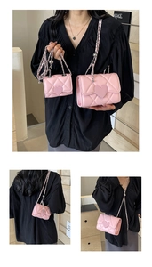Detail of pink quilted crossbody bag featuring heart-shaped lock and woven chain strap