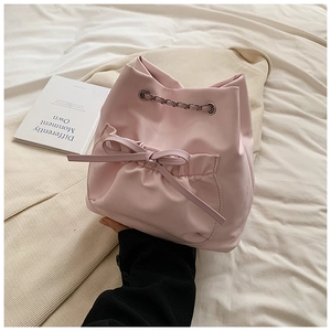 Detalle de bolso tipo cubo rosa con adorno de lazo y correa de cadena de metal