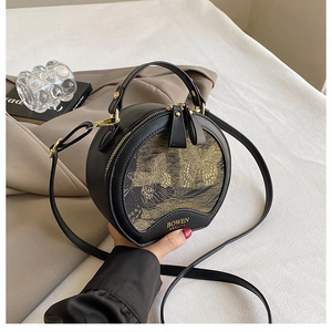 Detail of round black leather handbag with exquisite gold butterfly embroidery and logo