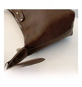 Close-up of brown textured leather handbag with diamond stitching and silver hardware