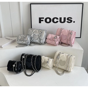Close-up of quilted chain bags in four colors with heart-shaped clasps on a display