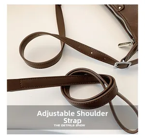 Detail of adjustable leather shoulder strap with silver buckle on a brown bag