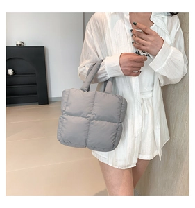 Model wearing a gray quilted down puffer tote bag with puffy padded handles