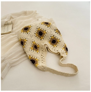 Détail du motif tournesol au crochet sur un sac cabas beige tissé avec longue lanière