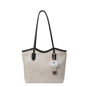 Chic cream tote bag with black handles and plush charm accessory for commuting