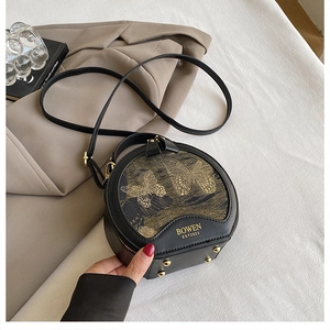 Detail of black leather round bag with golden butterfly embroidery and bottom studs