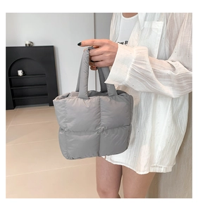 Close-up of a quilted grey puffer tote bag with soft padded handles and grid pattern
