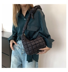 Primer plano de bolso acolchado negro con detalle de nudo elegante en la correa al hombro