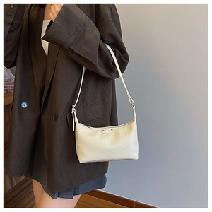 Detail showing cream quilted dumpling bag with adjustable strap on a shoulder
